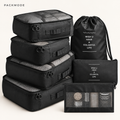 PACKMODE complete black seven-piece travel organizer set on warm ivory background